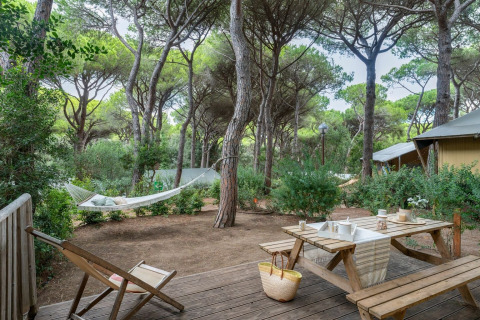 Terras van de Country Lodge Large safaritent in Sandaya Etruria, Italië, met hangmat en picknickbank tussen bomen.