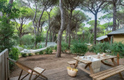 Terrasse en bois du lodge safari Country Lodge Large à Sandaya Etruria, Italie, avec hamac et banc de pique-nique.