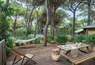 Terras van de Country Lodge Large safaritent in Sandaya Etruria, Italië, met hangmat en picknickbank tussen bomen.