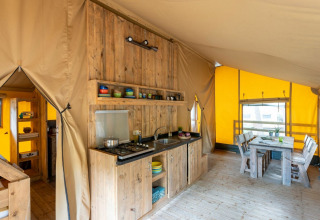 Indretning af et rummeligt teltkøkken og spiseplads i Country Lodge Large på Sandaya Etruria i Italien.