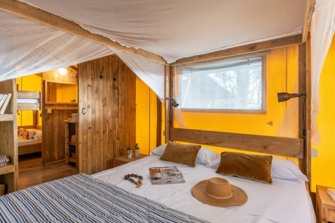 Habitación de tienda safari con cama doble y literas en Country Lodge Large, Sandaya Etruria, Italia.