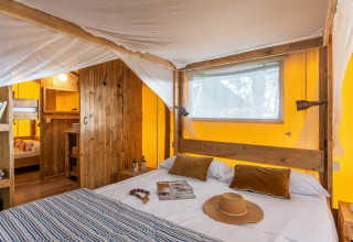 Safari telt værelse med dobbeltseng og køjesenge i Country Lodge Large, Sandaya Etruria, Italien.