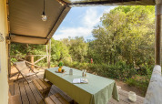 Outdoor covered terrace with wooden table and benches at Lodge Safari in Sandaya Etruria, Italy.