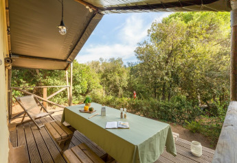 Outdoor covered terrace with wooden table and benches at Lodge Safari in Sandaya Etruria, Italy.