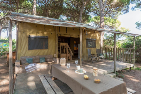 Safari tent Lodge Oasi with wooden deck and outdoor dining table at Sandaya Etruria campsite in Italy.