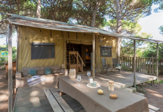 Safari tent Lodge Oasi met houten terras en picknicktafel bij Sandaya Etruria camping in Italië.