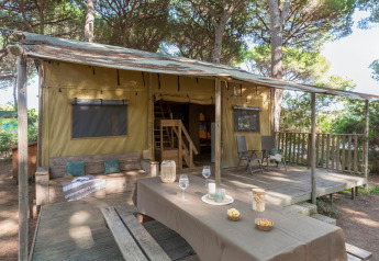 Safari tent Lodge Oasi met houten terras en picknicktafel bij Sandaya Etruria camping in Italië.