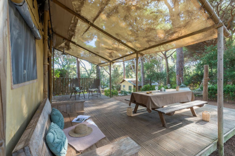 Outdoor deck at Lodge Oasi, Sandaya Etruria in Italy, with picnic table, hammock and view of the pine woods.