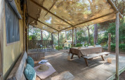 Terrasse extérieure de la Lodge Oasi au Sandaya Etruria, Italie, avec table pique-nique, hamac et forêt.