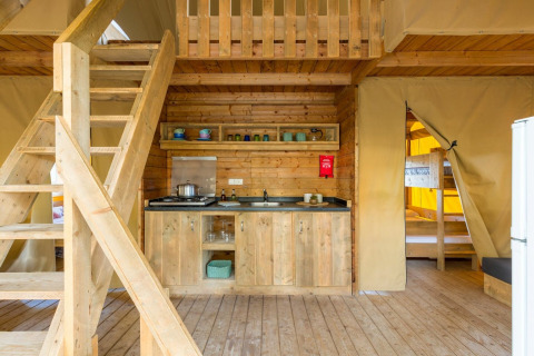 Interior view of the Lodge Oasi safari tent at Sandaya Etruria in Italy, showing kitchen and loft.