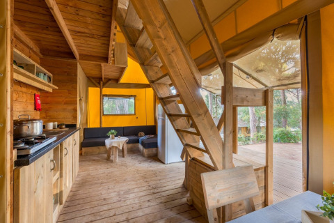 Interior view of Lodge Oasi safari tent at Sandaya Etruria in Italy, featuring wooden decor and forest views.