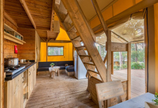 Interior view of Lodge Oasi safari tent at Sandaya Etruria in Italy, featuring wooden decor and forest views.