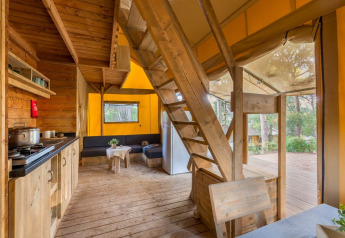 Interior view of Lodge Oasi safari tent at Sandaya Etruria in Italy, featuring wooden decor and forest views.