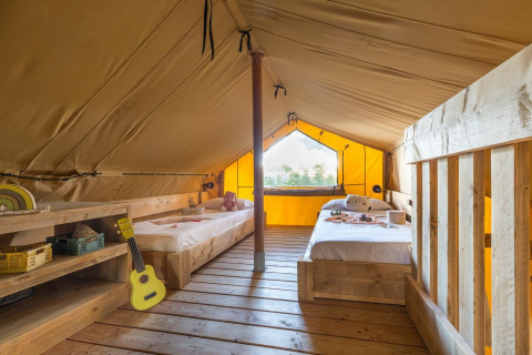 Interior of Lodge Oasi safari tent at Sandaya Etruria in Italy, featuring two single beds and wood floor.