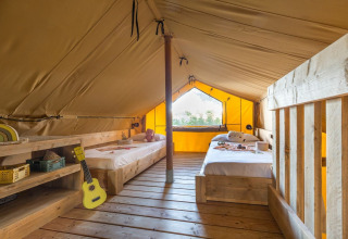 Interiør af Lodge Oasi safari telt på Sandaya Etruria i Italien med to enkeltsenge og trægulv.