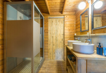 Modern wooden bathroom with double sinks, mirrors, and shower in Lodge Oasi, Sandaya Etruria, Italy.