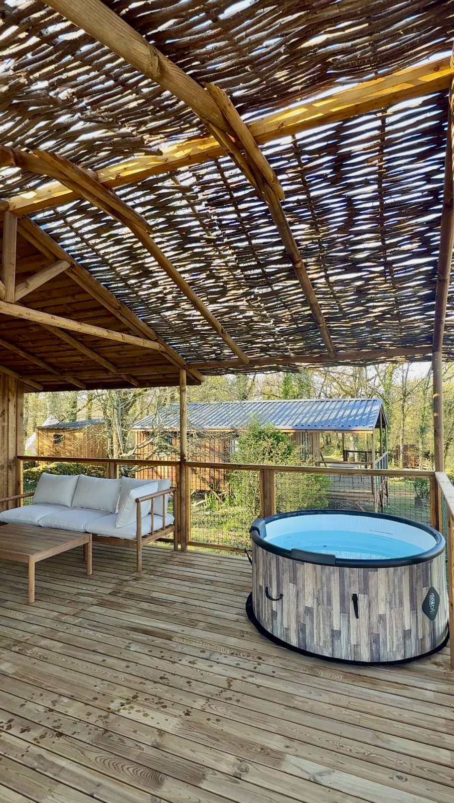 Houten terras met jacuzzi en loungebank bij Minca cabin, Camping Domaine de la Faurie, Frankrijk, met uitzicht.