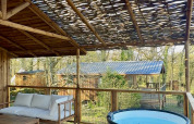 Terraza de madera con jacuzzi en la cabaña Minca en Camping Domaine de la Faurie, Francia, vista al valle.