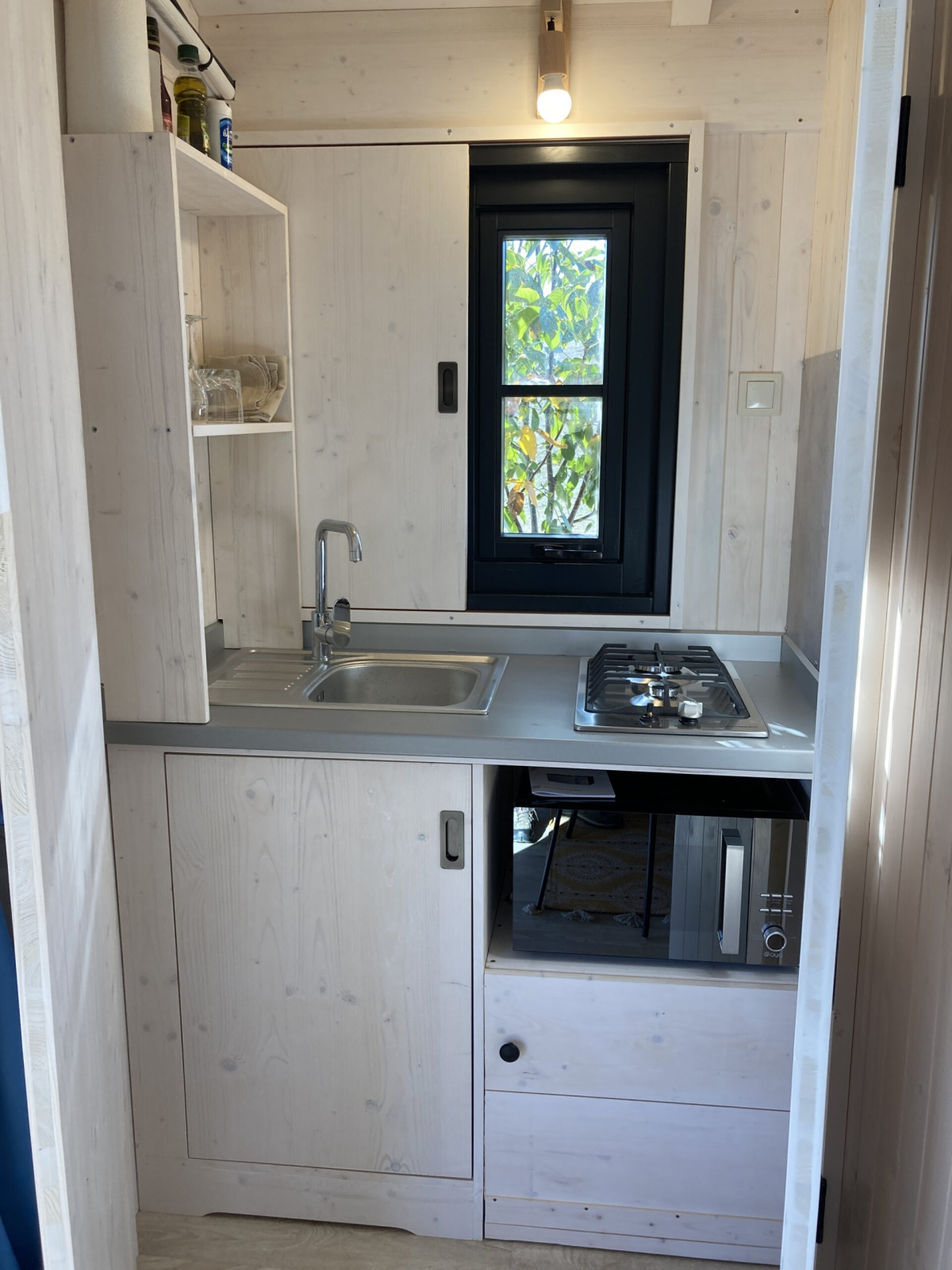Kleine keuken in Minca cabin met gootsteen, kookplaat en magnetron op Camping Domaine de la Faurie, Frankrijk.