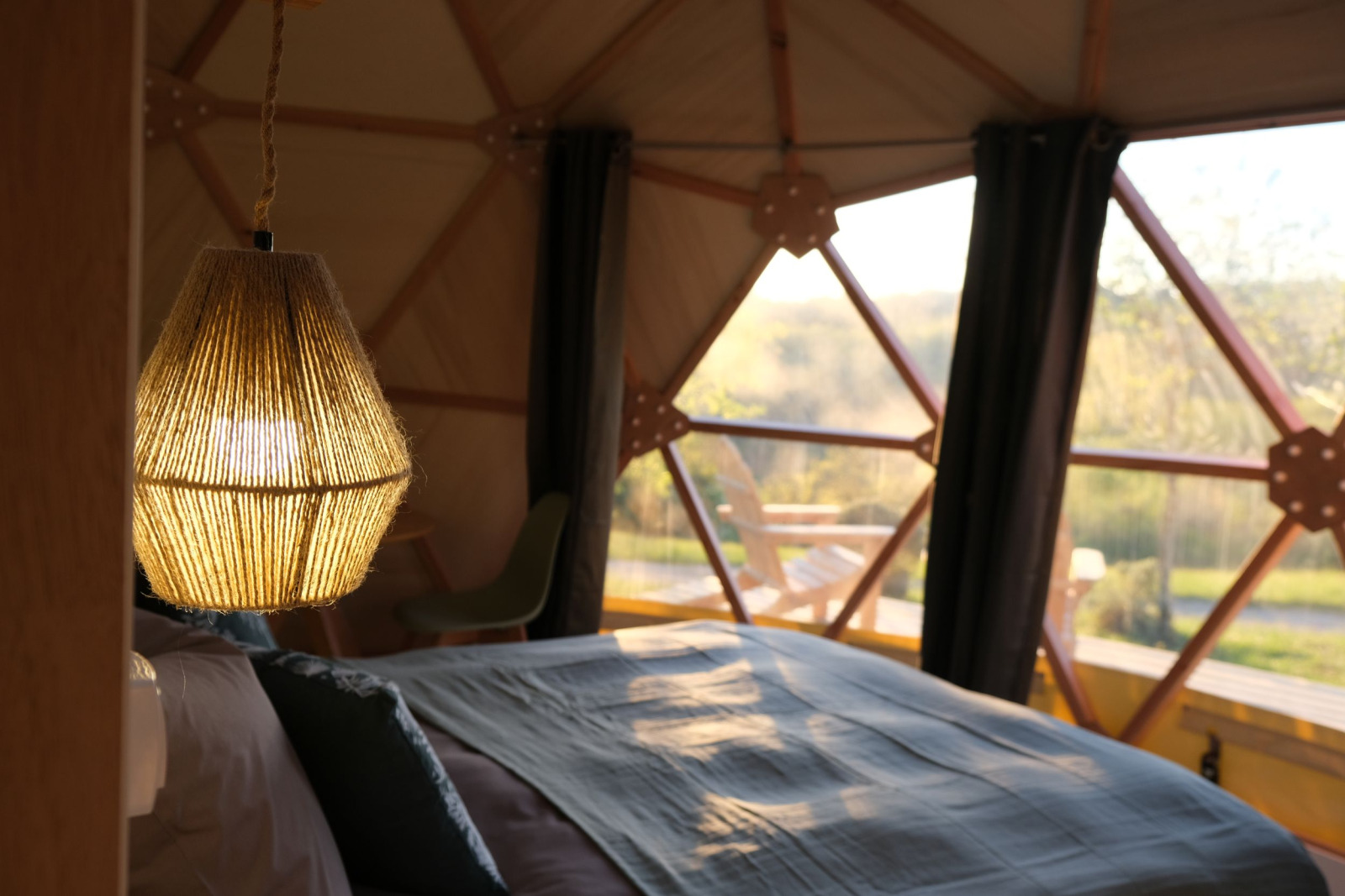 Interieur van Skydome Ushuaïa bij Camping Domaine de la Faurie in Frankrijk met bed en hanglamp bij raam.