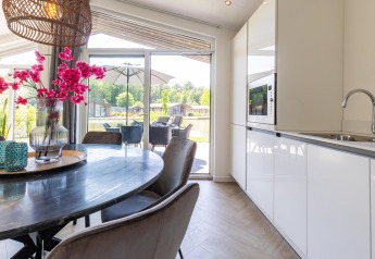 Lichte keuken en eetruimte met uitzicht op terras bij Villa Waterzicht Luxe met Sauna, Molenvelden, Nederland.