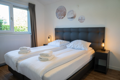 Dormitorio moderno con dos camas individuales, ropa de cama blanca y lámparas en Villa Waterzicht Comfort, Molenvelden.