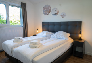 Modern twin bedroom with white linens, bedside lamps and wall art at Villa Waterzicht Comfort, Molenvelden.