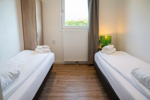 Camera con due letti singoli, armadio in legno e lampada verde a Villa Waterzicht Comfort, Molenvelden.