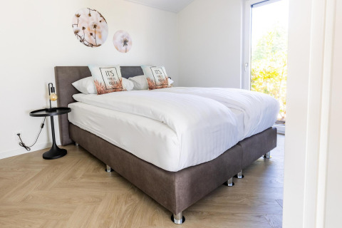 Lyst soveværelse i Villa Waterzicht Luxe 4, Holiday park Molenvelden, med dobbeltseng og moderne dekoration.