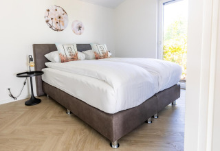 Dormitorio luminoso en Villa Waterzicht Luxe 4, Holiday park Molenvelden, Países Bajos, con cama doble moderna.
