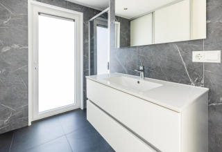 Moderne badeværelse i Villa Waterzicht Luxe 4 på Holiday park Molenvelden, Holland, med grå marmorvægge.