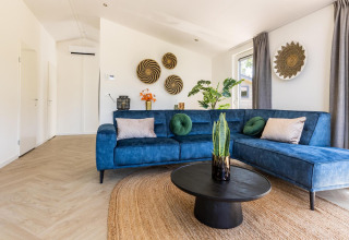 Modern living room with blue sofa at Villa Waterzicht Luxe 4 in Holiday park Molenvelden, Netherlands.