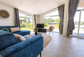 Salón moderno en Villa Waterzicht Luxe 4 en Holiday park Molenvelden, con sofá azul y grandes ventanales.