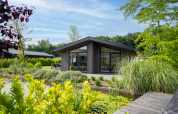 Villa Waterzicht Luxe 6 in vakantiepark Molenvelden, omgeven door natuur en een vijver met lelies.
