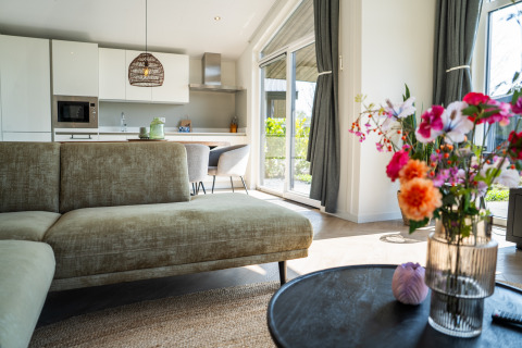 Helles Wohnzimmer mit Küche in der Villa Waterzicht Luxe 6, Holiday park Molenvelden, Niederlande.