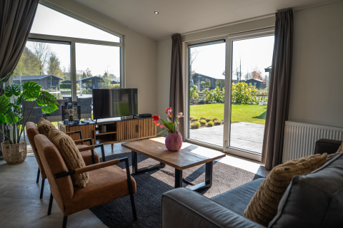 Soggiorno moderno in Villa Waterzicht Luxe 6, Holiday park Molenvelden, con grandi finestre e vista sul giardino.