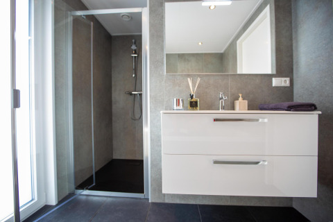 Modern bathroom featuring a glass shower, large mirror, and white vanity in Villa Waterzicht Luxe 6.