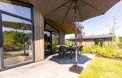 Udendørs terrasse med parasol og spisebord på Villa Waterzicht Luxe met Ligbad, Holiday park Molenvelden, Holland.