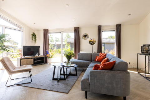 Lyst og moderne stue i Villa Waterzicht Luxe met Ligbad på Holiday park Molenvelden, Nederlandene.