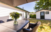 Outdoor dining area at White Lodge in Holiday park Molenvelden, Netherlands, with vase and modern chairs.