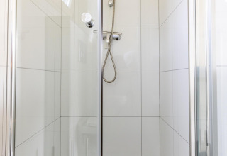 Moderne Duschkabine mit Glastüren und weißen Fliesen in der White Lodge im Holiday park Molenvelden, Niederlande.