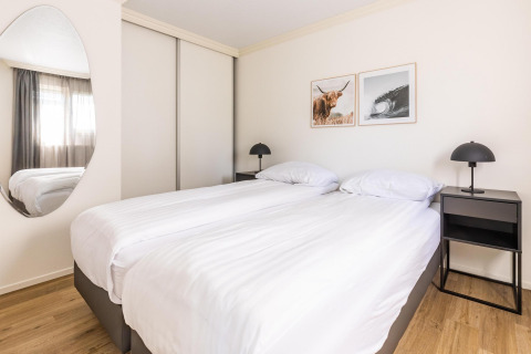 Helles Schlafzimmer mit zwei Einzelbetten, moderner Dekor und Wandbildern im White Lodge, Molenvelden.