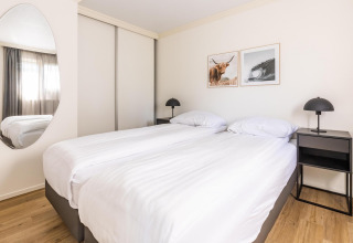Bright bedroom with twin beds, minimalist decor and wall art at White Lodge, Holiday park Molenvelden.