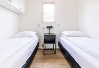 Dormitorio minimalista moderno con dos camas individuales en White Lodge, Holiday park Molenvelden, Países Bajos.