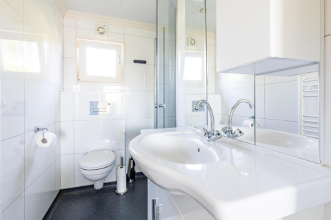 Modernes Badezimmer mit Doppelwaschbecken, Spiegel und Toilette in der White Lodge, Ferienpark Molenvelden.