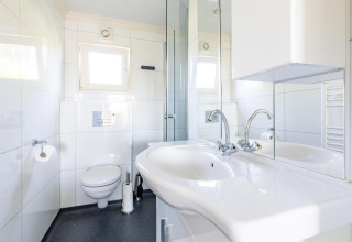 Modernes Badezimmer mit Doppelwaschbecken, Spiegel und Toilette in der White Lodge, Ferienpark Molenvelden.