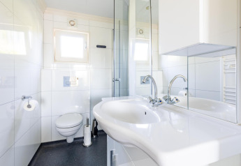 Baño moderno con lavabo doble, espejos grandes y sanitario en White Lodge, Holiday park Molenvelden.