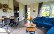 Acogedora sala y comedor en Wood Lodge Waterzicht con sofá azul y decoración de madera, parque Molenvelden, Países Bajos.