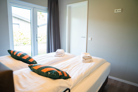 Modern bedroom at Wood Lodge Waterzicht, Holiday park Molenvelden, Netherlands, with bright daylight.