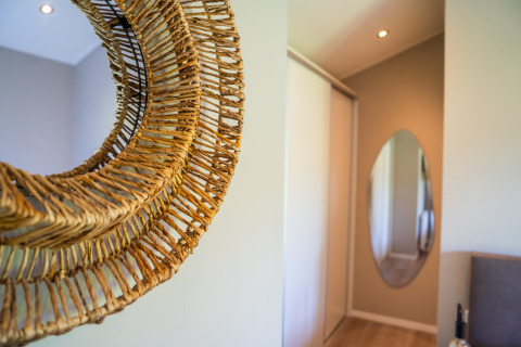 Interno di Wood Lodge Waterzicht con decorazione in vimini e specchio ovale, Holiday park Molenvelden, Paesi Bassi.